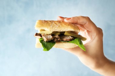 Biftekli sandviç ışık arka plan üzerinde tutan kadın