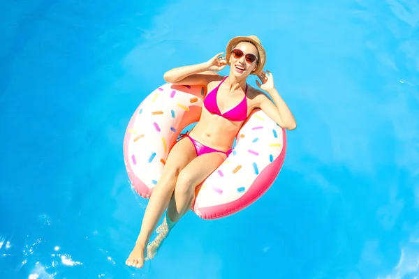 Genç kadın yüzme havuzunda şişme çörek üzerinde rahatlatıcı — Stok fotoğraf