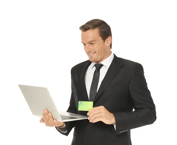 Jeune homme d'affaires tenant une carte de crédit tout en utilisant un ordinateur portable sur fond blanc — Photo