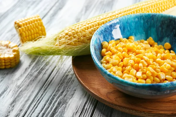 Mazorca de maíz y tazón con granos en la bandeja — Foto de Stock
