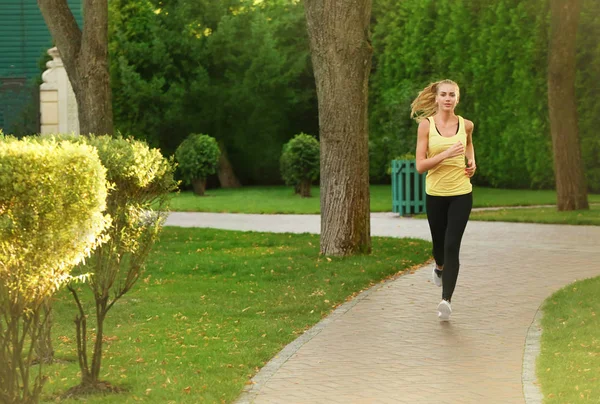 Jovem mulher esportiva correndo no parque verde — Fotografia de Stock
