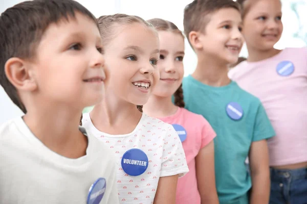 Дети в футболках с пуговицами добровольцев — стоковое фото