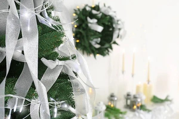 Schöne Tanne mit silbernen Bändern und Weihnachtsbeleuchtung — Stockfoto