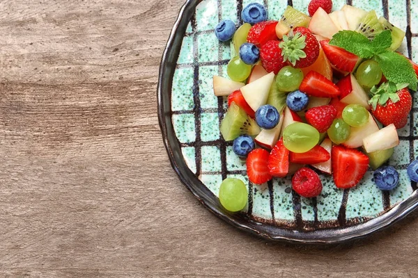 Teller mit Obstsalat auf Holztisch — Stockfoto