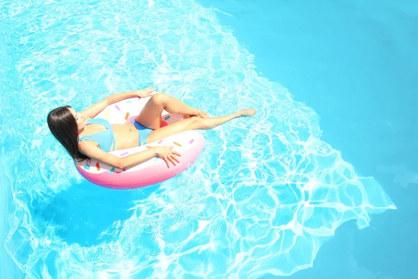 수영장에서 풍선 반지에 일광욕 하는 젊은 아름 다운 여자 — 스톡 사진