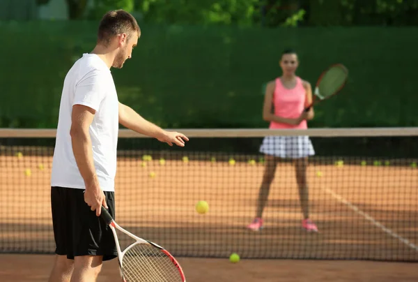 Mladý pár hrát tenis na kurtu — Stock fotografie
