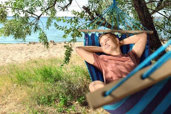 Jovem relaxante na rede ao ar livre — Fotografia de Stock