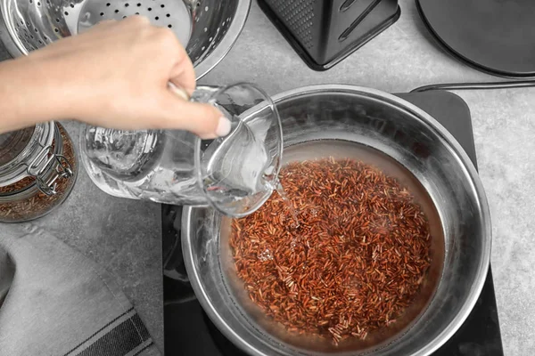 Woman pouring water into bowl with boiling rice — Stock Photo, Image