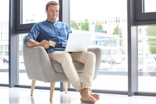 Junger Mann mit Kreditkarte, während er zu Hause Laptop benutzt — Stockfoto