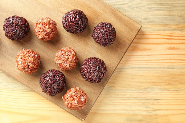 Cooked different rice balls on wooden board — Stock Photo, Image