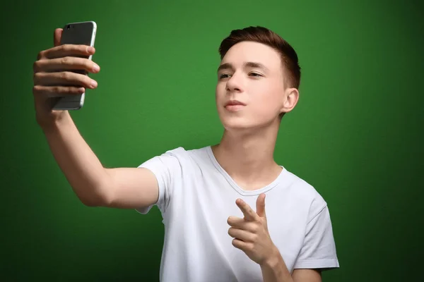 Cute teenage boy with mobile phone on color background — Stock Photo, Image