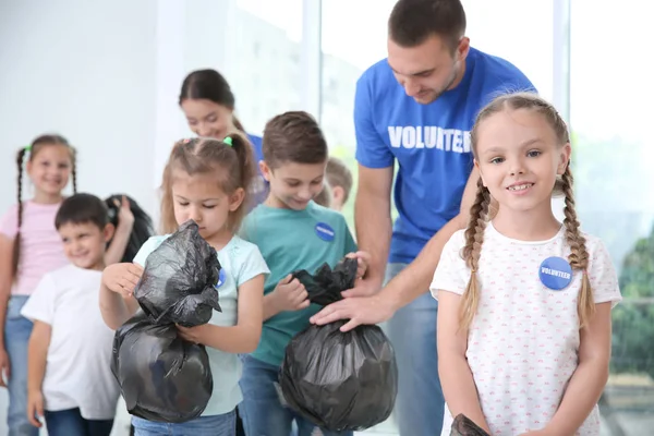 Glückliche Freiwillige und Kinder mit Müllsäcken im Haus — Stockfoto