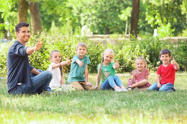 Grupo de crianças com professor no parque no dia ensolarado — Fotografia de Stock