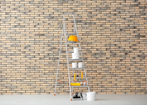 Composición con herramientas de decorador y pintura en escalera cerca de la pared de ladrillo — Foto de Stock