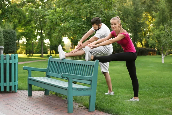 Young sporty couple doing exercise in green park — Stock Photo, Image