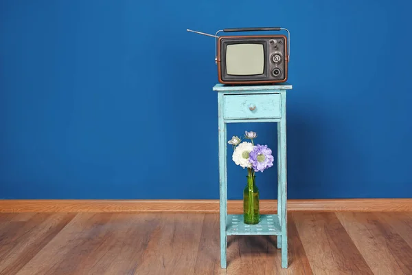 Pequeño televisor viejo en la mesa contra la pared de color — Foto de Stock