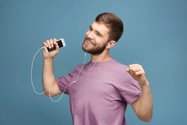 Young man listening to music against color background — Stock Photo, Image
