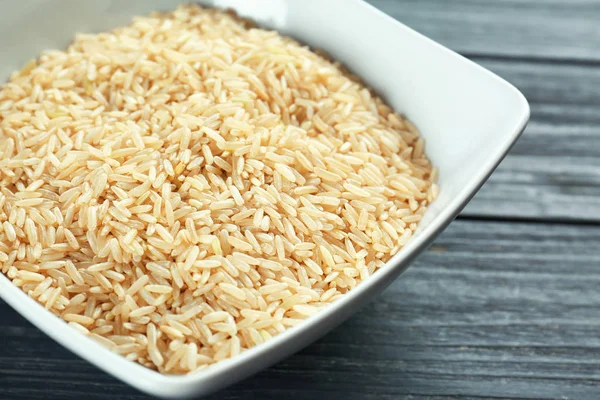 Schüssel mit rohem Reis auf Holztisch — Stockfoto