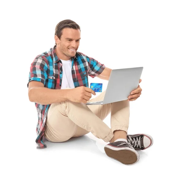 Jeune homme tenant ordinateur portable et carte de crédit sur fond blanc — Photo