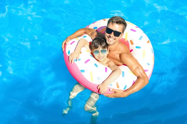 若い男と息子のスイミング プールで膨らませてドーナツと — ストック写真