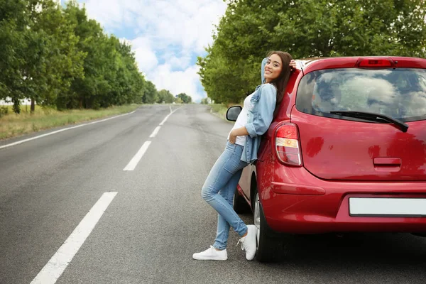 Молодая женщина опирается на автомобиль на открытом воздухе — стоковое фото