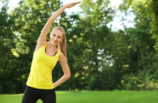 Young sporty woman doing exercise in green park — Stock Photo, Image