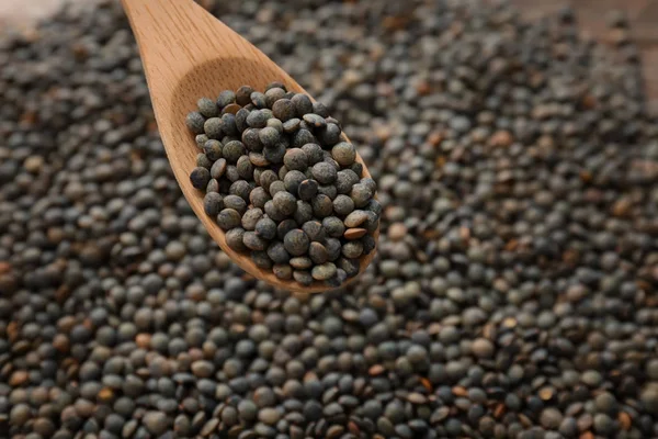 Cucchiaio con lenticchie verdi su fondo sfocato — Foto Stock