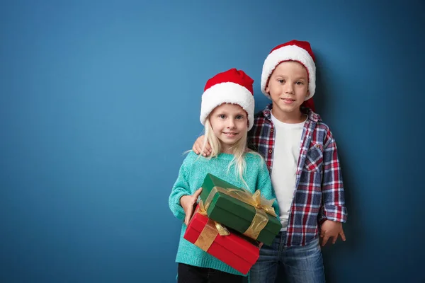 逗人喜爱的孩子与圣诞节礼物在颜色背景 — 图库照片