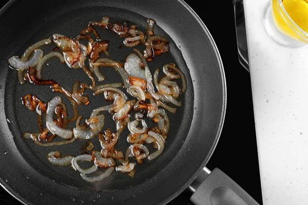 Frying pan with onion on stove — Stock Photo, Image