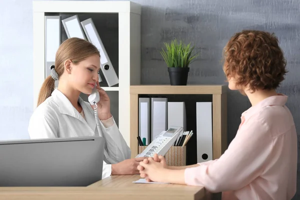 Junge Empfangsdame mit Klientin im Krankenhaus — Stockfoto