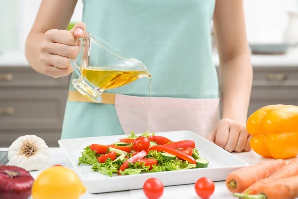 Mujer vertiendo aceite de cocina en ensalada vegetal — Foto de Stock