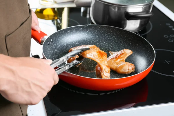 Человек готовит куриные крылышки на сковородке — стоковое фото