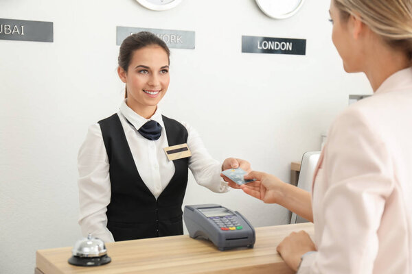 Молодая женщина платит за номер в отеле
