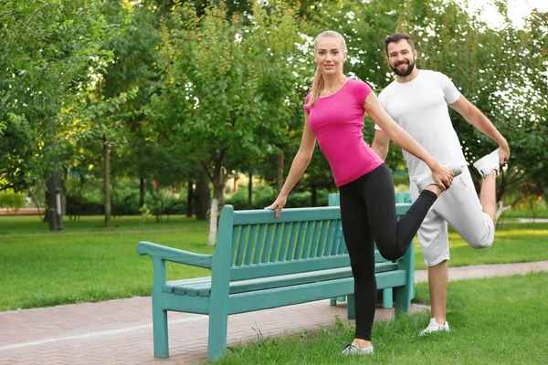 Sportliches junges Paar beim Turnen im grünen Park — Stockfoto