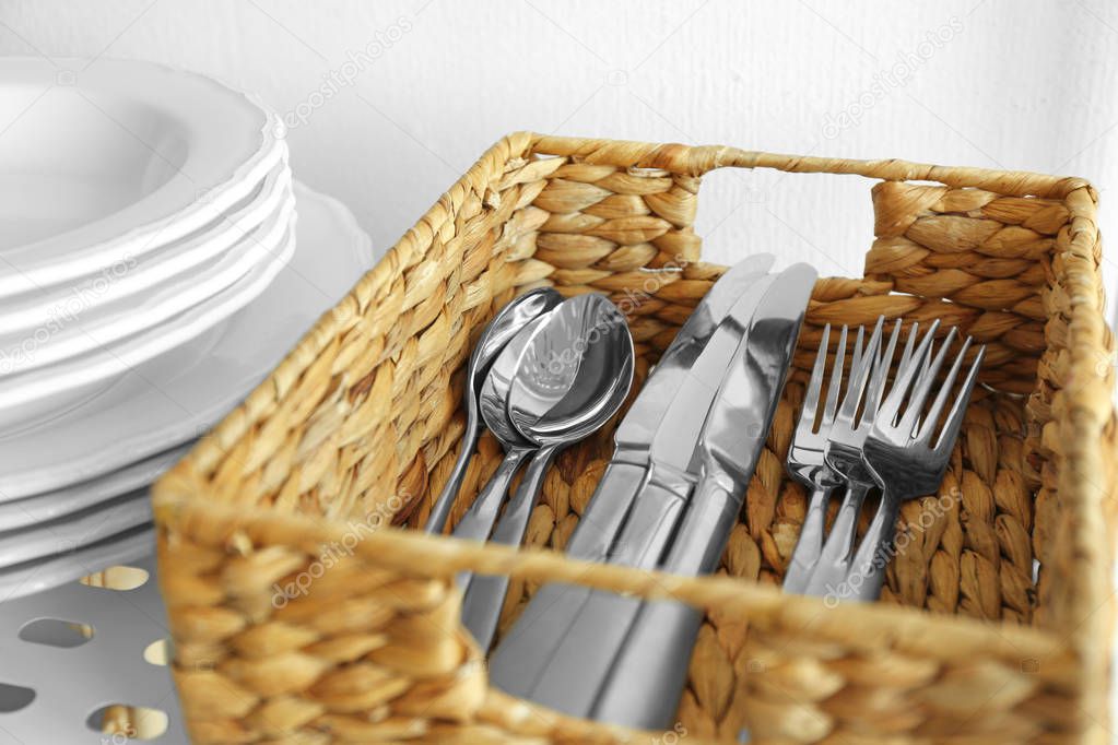 Cutlery in wicker basket on shelf
