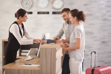 Resepsiyondaki otel odası için ödeme yapan genç çift.