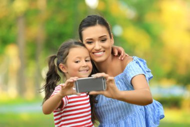 Sevimli küçük kız ve annesi selfie Park'ta güneşli günde alarak.