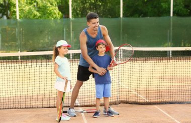 Tenis kortunda Küçük çocuklu genç eğitmeni
