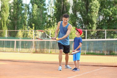 Tenis kortunda küçük çocuk ile genç eğitmeni