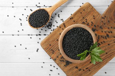 Kase ve ahşap masa üzerinde siyah mercimek kaşıkla