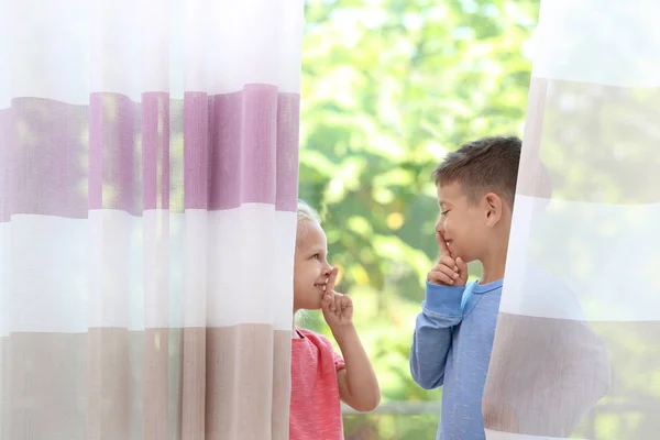 Bonito crianças se escondendo atrás de cortinas em casa — Fotografia de Stock