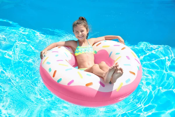 Menina bonito no anel inflável na piscina — Fotografia de Stock