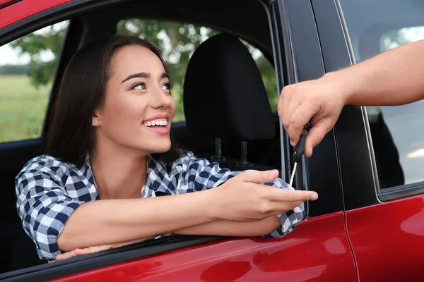 Man passing car key to young woman outdoors — Stock Photo, Image