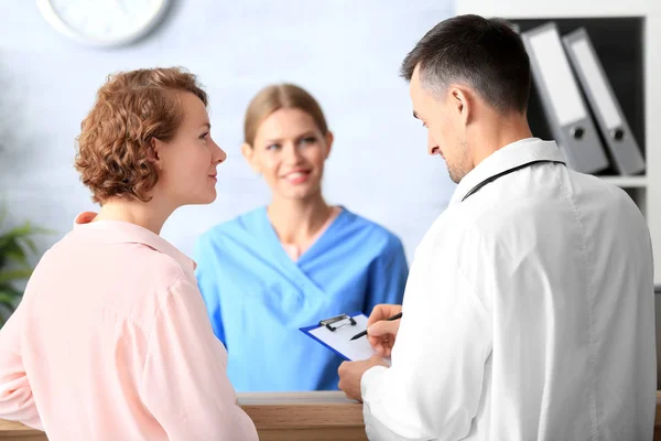 Receptionist and doctor with client in hospital — Stock Photo, Image