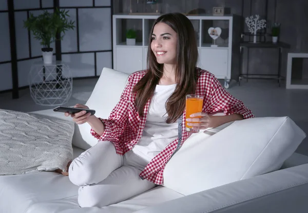 Young woman watching TV on sofa at night — Stock Photo, Image