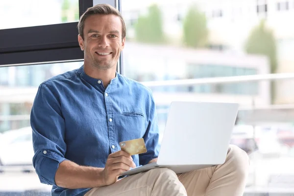 Junger Mann mit Kreditkarte, während er zu Hause Laptop benutzt — Stockfoto