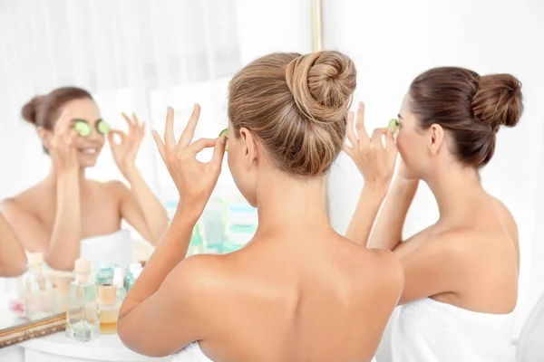 Young women with cucumber slices in bathroom — Stock Photo, Image