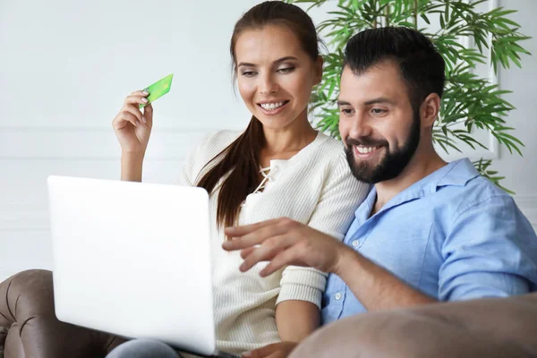 Unga par med laptop och kreditkort hemma. Internet shopping koncept — Stockfoto