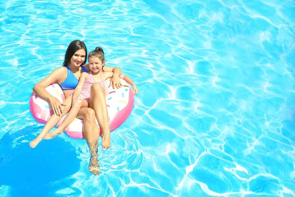 Mujer joven con linda hija en anillo inflable en la piscina — Foto de Stock