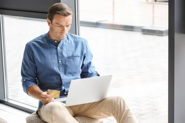 Junger Mann mit Kreditkarte, während er zu Hause Laptop benutzt — Stockfoto